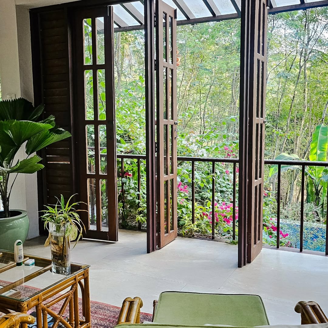 Open wooden doors and rattan furniture with a view through to the lush garden and pool — The Red Hen Homestead interior